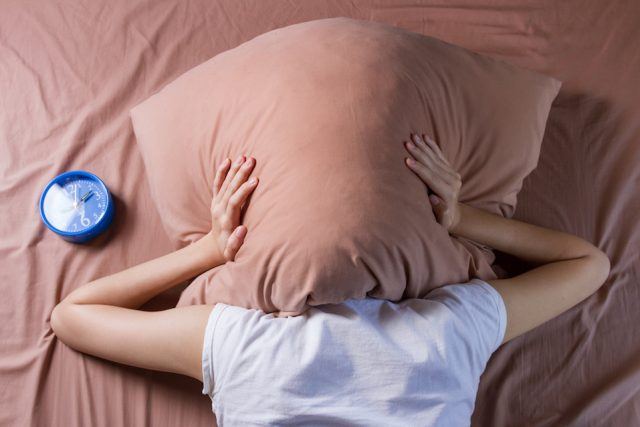 woman-cover-her-head-with-pillow-640x427
